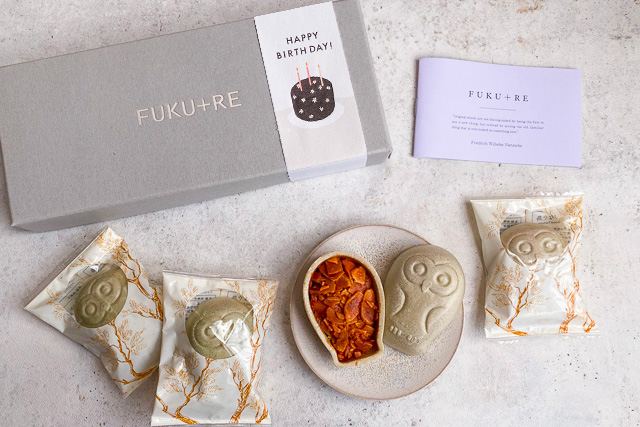 FUKU+REのギフト箱に誕生日ケーキの帯を添えた、おしゃれなお菓子の誕生日プレゼント。