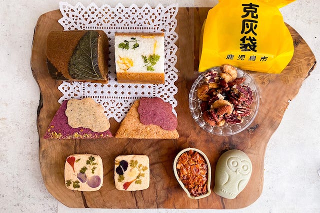 鹿児島の素材を活かした華やかなスイーツ詰め合わせ。桜島サブレやふくれ菓子、克灰袋クッキーなどが木のプレートに美しく並べられている