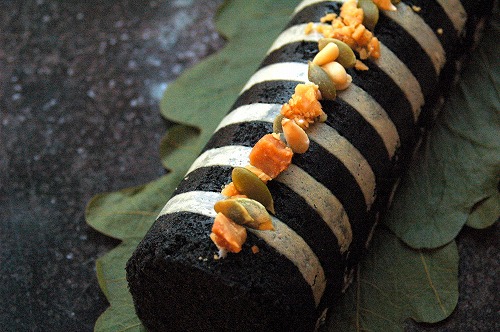 鹿児島の特産素材を使ったスイーツ。黒ごまと白ごまのストライプ模様が美しいロールケーキに、ナッツやドライフルーツがトッピングされている
