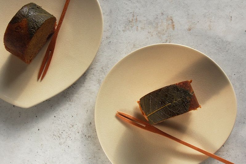 小皿に盛った鹿児島ふくれ菓子「サンボ」。桜の葉に包まれた黒糖味のふくれ生地から、優しく懐かしい香りが漂うお取り寄せスイーツ。