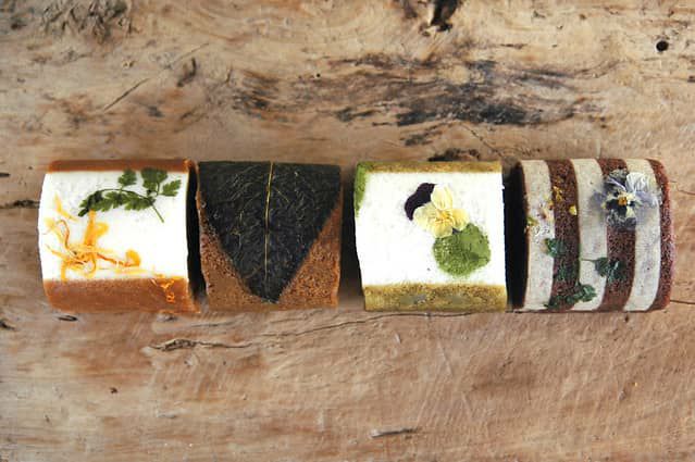 ウッドボードに並ぶ鹿児島ふくれ菓子4種。異なる色味と装飾が映える黒糖・桜島小みかん・緑茶・すもも味の蒸し菓子詰め合わせ