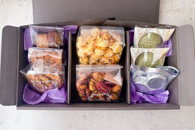 FUKU+REのギフトボックスを開けた中身。焼き菓子、鰹節ポップコーン、芋飴ナッツなどが丁寧に詰められている