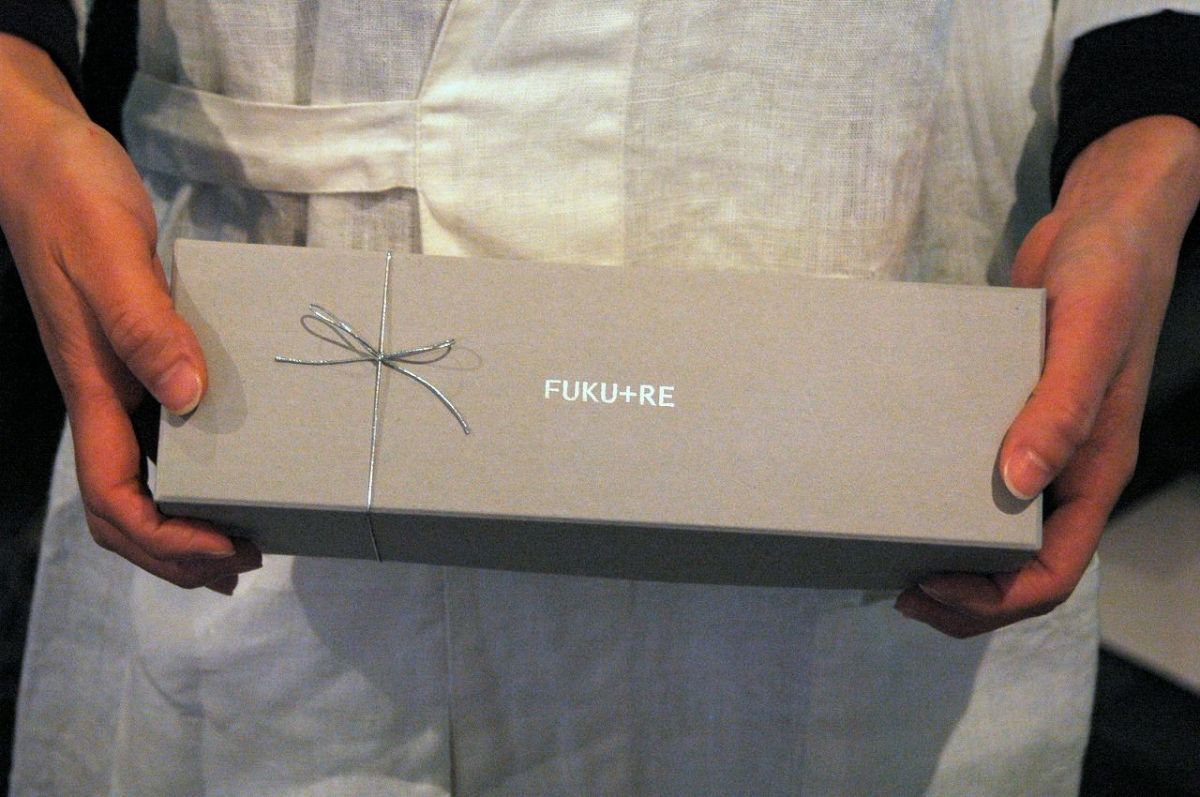 FUKU+REロゴ入りギフト箱を手に持つ様子。お礼やお返しに喜ばれる上品なお菓子ギフト。