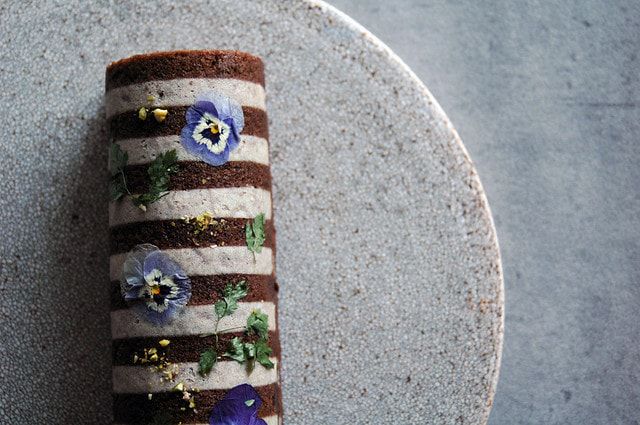 鹿児島ふくれ菓子「Peche mignon」11cm。すもも混ぜ込みココア生地にエディブルフラワーとハーブの華やかな飾り。ギフトにも映えるモダンデザイン。