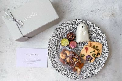 FUKU+REブランドのギフトボックスと、花の押し花クッキー、ナッツ、カラフルな焼き菓子、ゴースト型の和菓子を黒白模様の皿に盛り付けた上品なハロウィンスイーツセットの写真