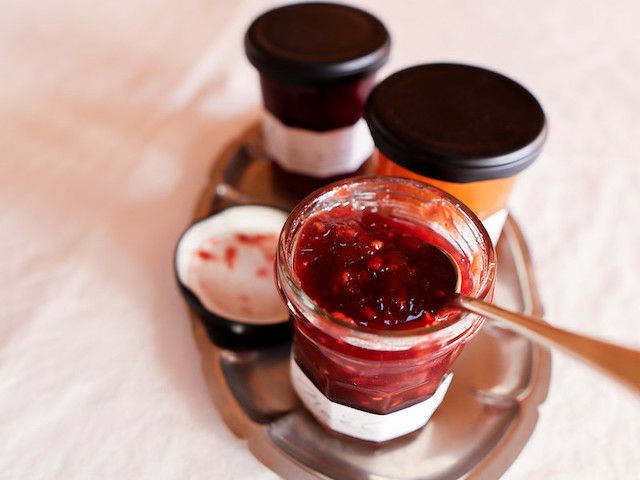 深い赤色のジャムが詰まったガラス瓶の商品写真。開封したジャムからスプーンですくい、上質な色味と際立つ粒感を写している。