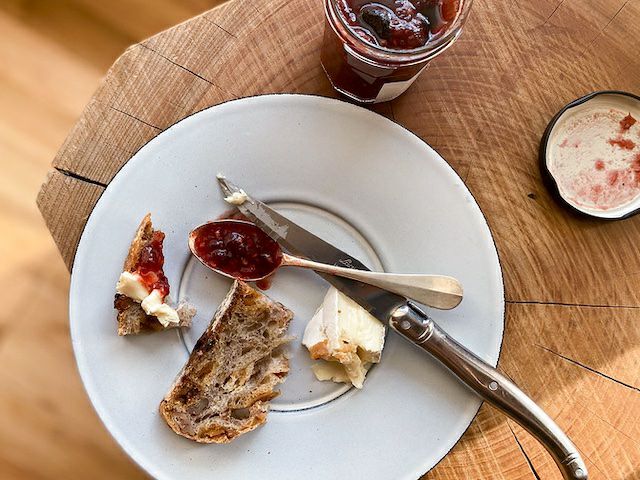 パンに赤いジャムを塗り、開封した瓶とともに並べた朝食シーン。ジャムの香りと使い方が伝わる構図。