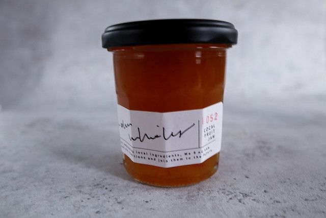 橙色のジャムが詰まったガラス瓶の商品写真。シンプルなラベルと上質な色味が際立ち、ギフトにも適した印象。